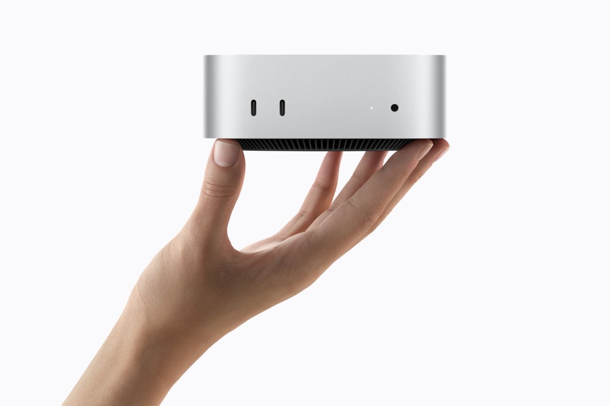 New Mac mini with M6 chip held in one hand, showing its two front USB-C ports